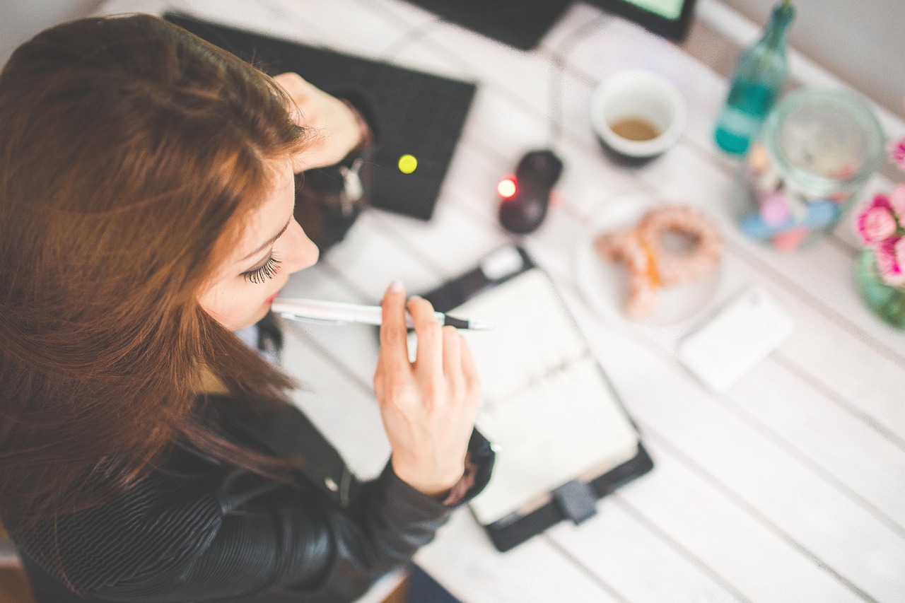 Femme réfléchissant avec un stylo près d'un carnet à son plan de communication d'association